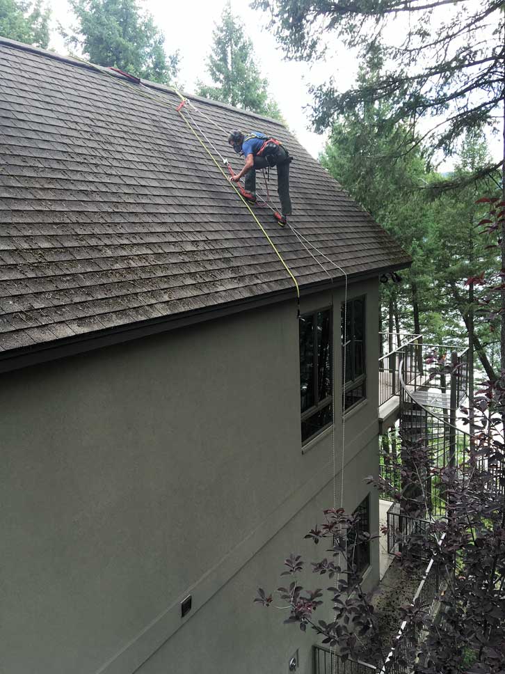 man working on tall house roof